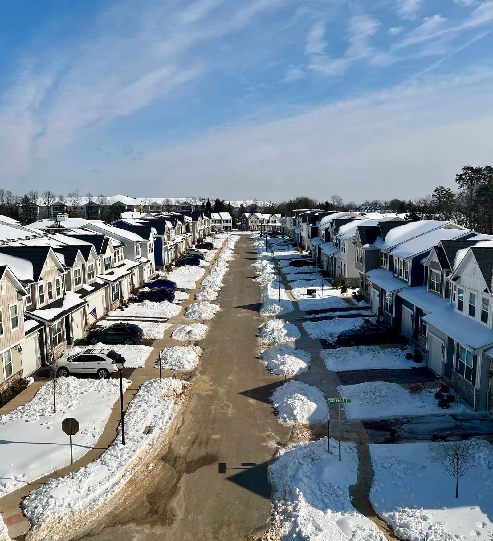 Snow-covered street of townhouses with bare trees